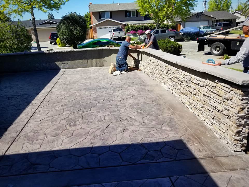 Stamped concrete driveway with a stacked stone-veneer retaining wall