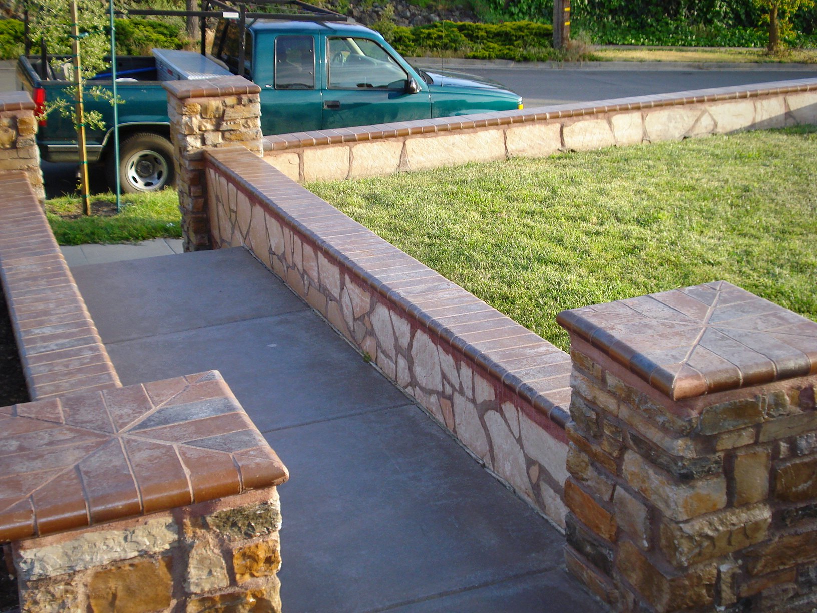 Stone-veneer seat walls with capped columns alongside a concrete walkway