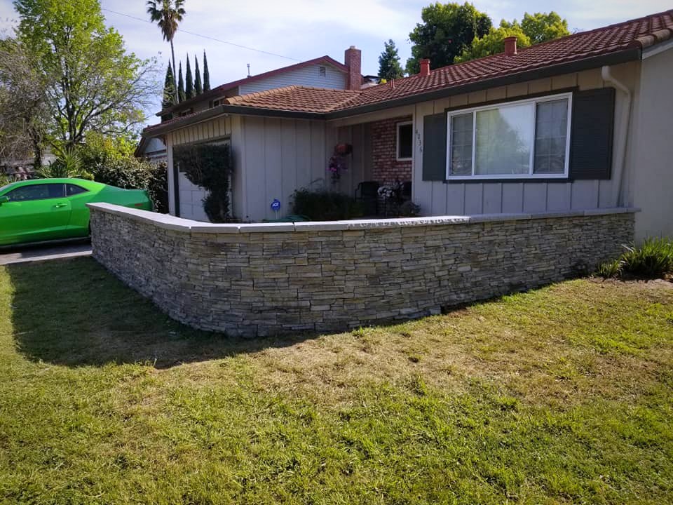 Curved stone veneer seat wall on front lawn