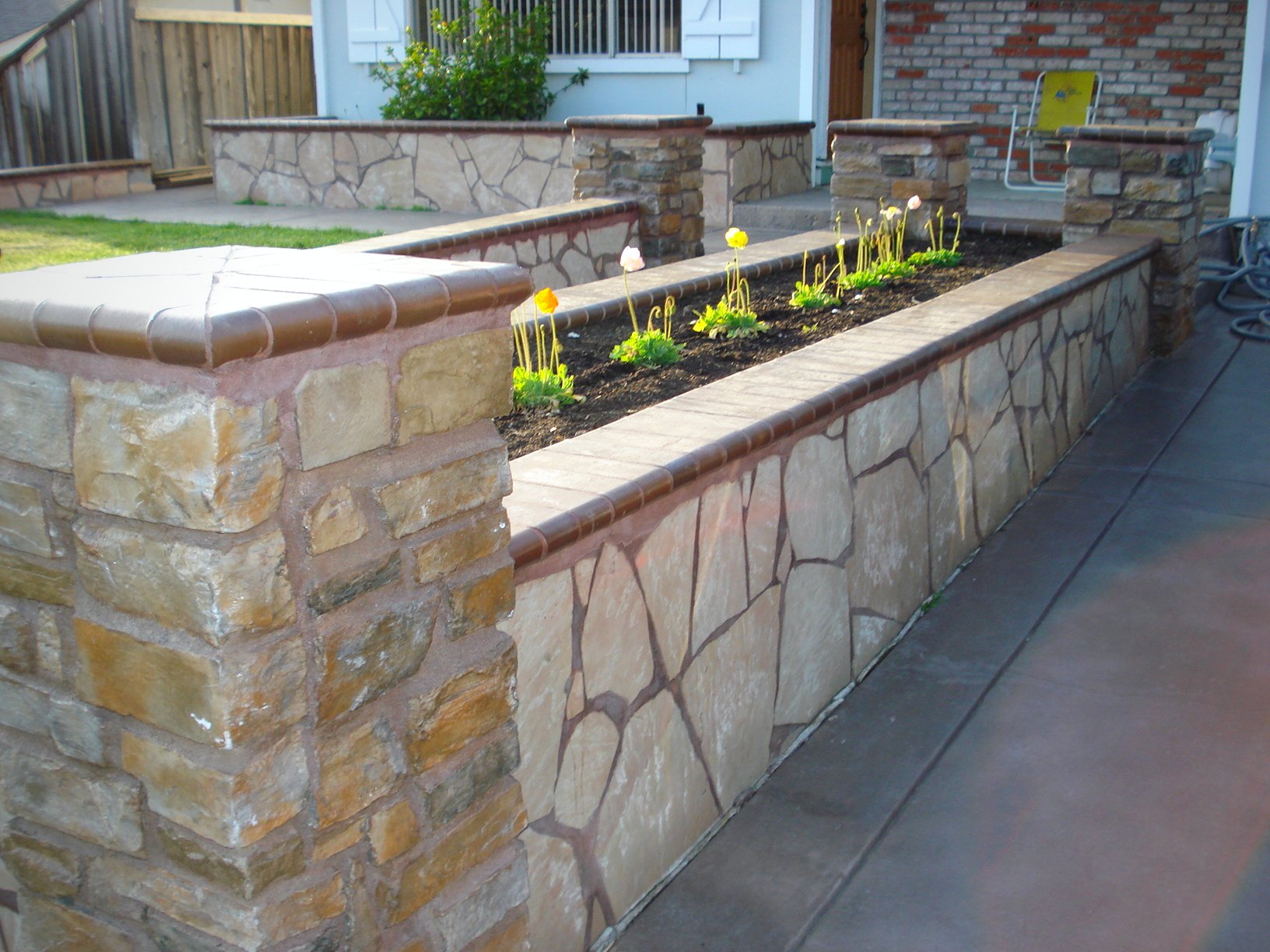 Stone planter walls with stamped driveway at dusk
