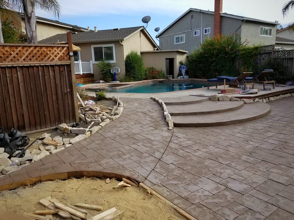 Stamped concrete pool deck with curved steps up to the pool